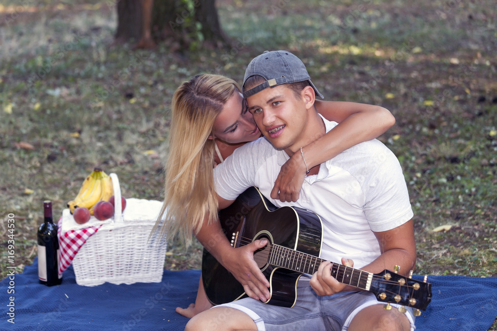 The young man plays guitar, while the girl enjoying the music