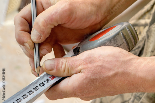 Man marking piece of pipe using pencil and tape measure. photo