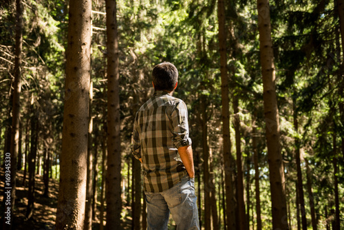 Active young adult man enjoy standing in wild pine forest on mountain in sunny summer day outdoor