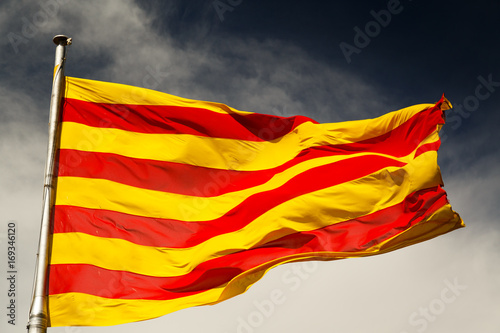 A close-up shot of a large sunlit Catalan flag against a dark sky photo