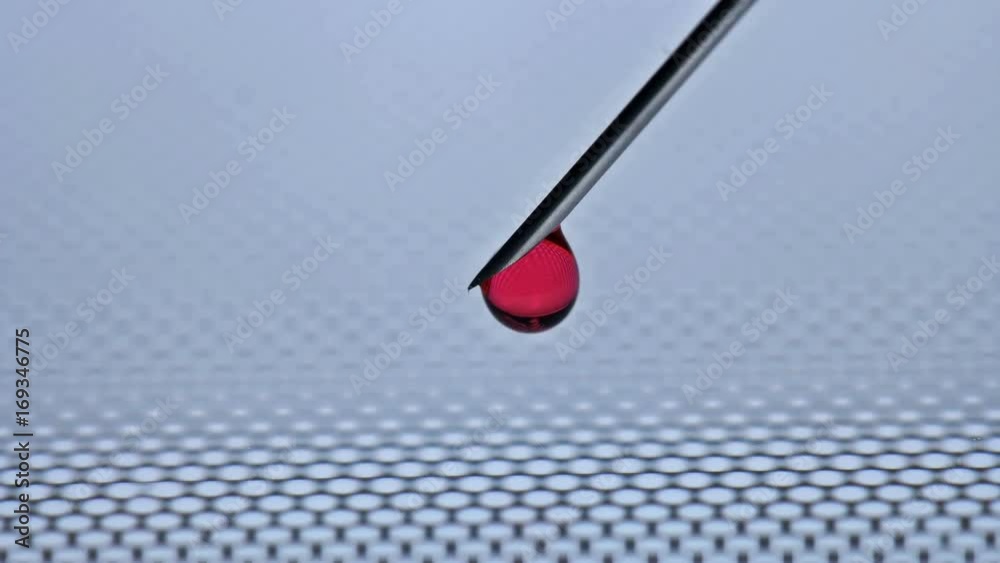 With a needle from the syringe flows a drop of red liquid With a needle from the syringe flows a drop of red liquid