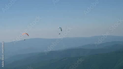 two paraglides flying in clear blue sky. photo