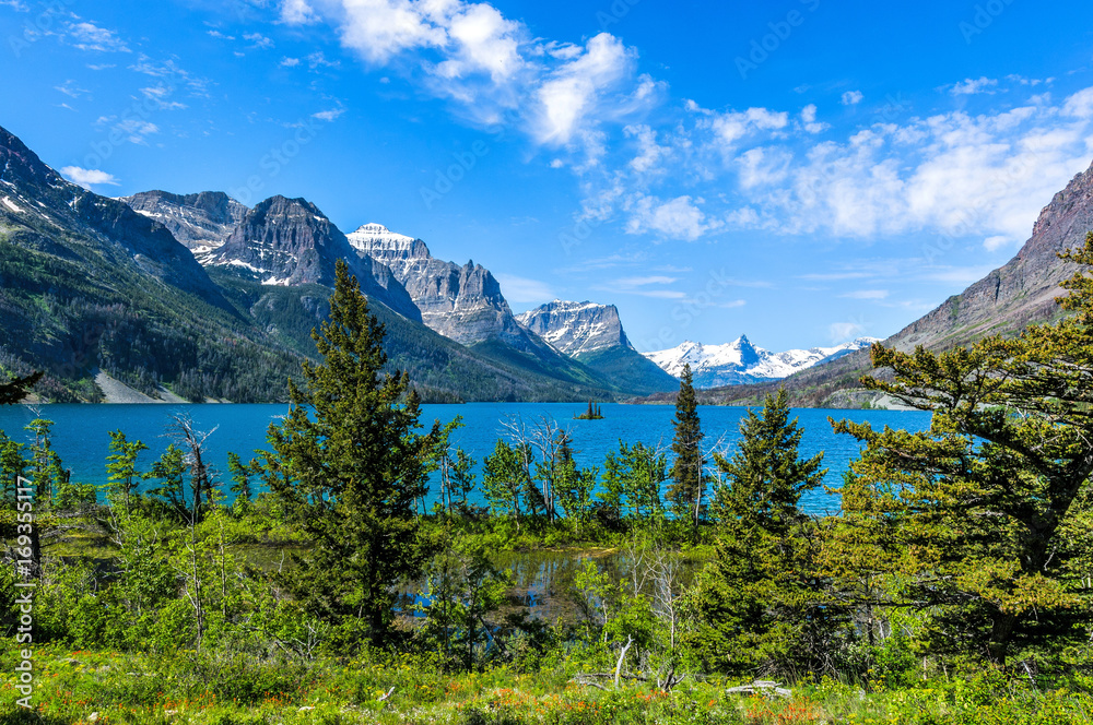 Spring at Saint Mary Lake - A panoramic view of high clouds passing over blue Saint Mary Lake and its surrounding steep mountains in Glacier National Park, Montana, USA.