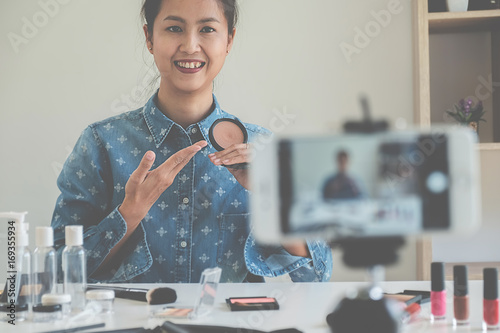 Young female blogger with smartphone recording video at home. beauty and technology concept