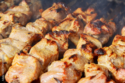 raw kebab grilling on metal skewer. Raw meat roasting at barbecue.