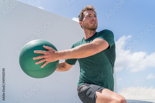 Fotografia Fitness man training at gym working out legs and abs doing lunges twisting the torso for core workout with medicine ball weight