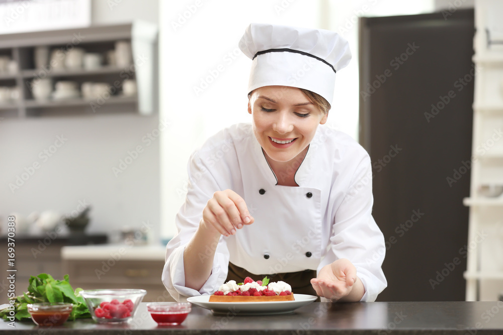 Female chef decorating tasty dessert in kitchen Female chef decorating tasty dessert in kitchen