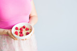 Woman's hands hold healthy and natural breakfast, oatmeal and raspberries in a bowl