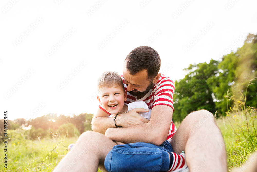 Hipster father and little son on green meadow. Sunny summer day. Hipster father and little son on green meadow. Sunny summer day.
