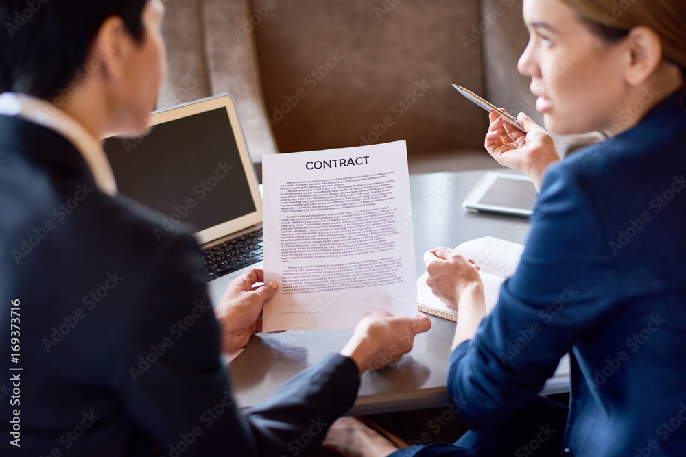 Φωτογραφία Back view of female business partners discussing terms of agreement before signi