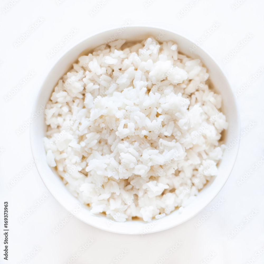 White cooked  rice in a white bowl over white background close up.