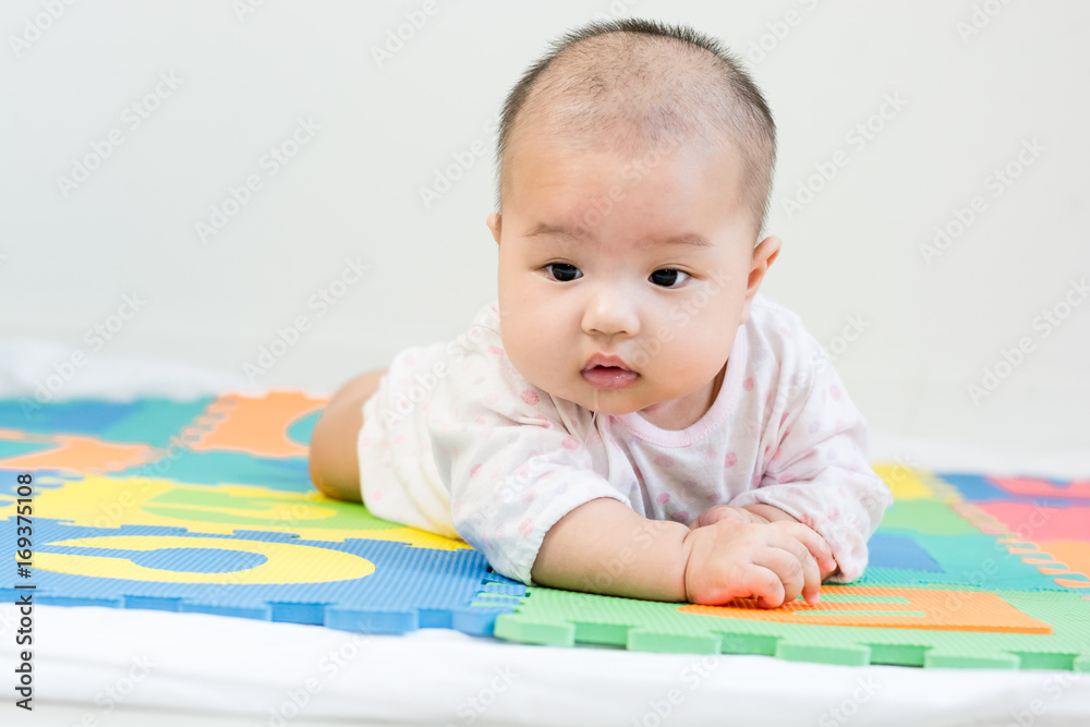 Portrait of adorable baby with saliva lying on the tummy on colorful eva foam, indoors Portrait of adorable baby with saliva lying on the tummy on colorful eva foam, indoors
