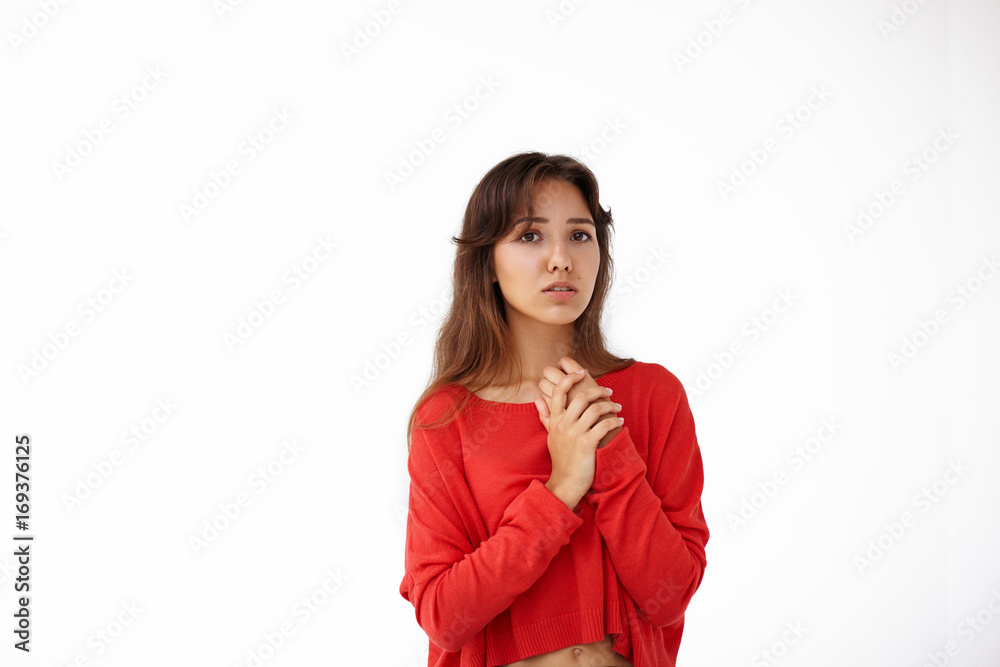 Concept of indecisiveness. Portrait of attractive brunette female dressed casually holding hands on her chest, having worried look while waiting for results of exams or job interview. Body language Concept of indecisiveness. Portrait of attractive brunette female dressed casually holding hands on her chest, having worried look while waiting for results of exams or job interview. Body language