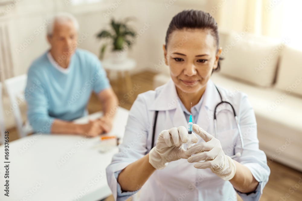 Cheerful positive nurse testing the syringe Cheerful positive nurse testing the syringe