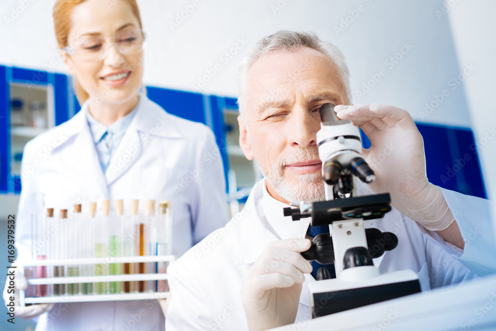 Portrait of positive scientist that looking into microscope Portrait of positive scientist that looking into microscope