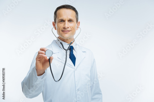 Happy medical worker using stethoscope over light background