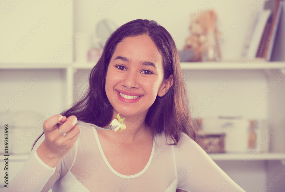 Positive young female eating salad