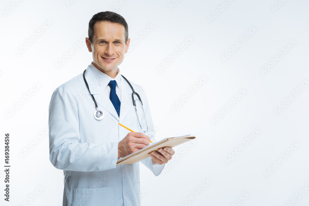 Cheerful male physician with notebook smiling into camera Cheerful male physician with notebook smiling into camera