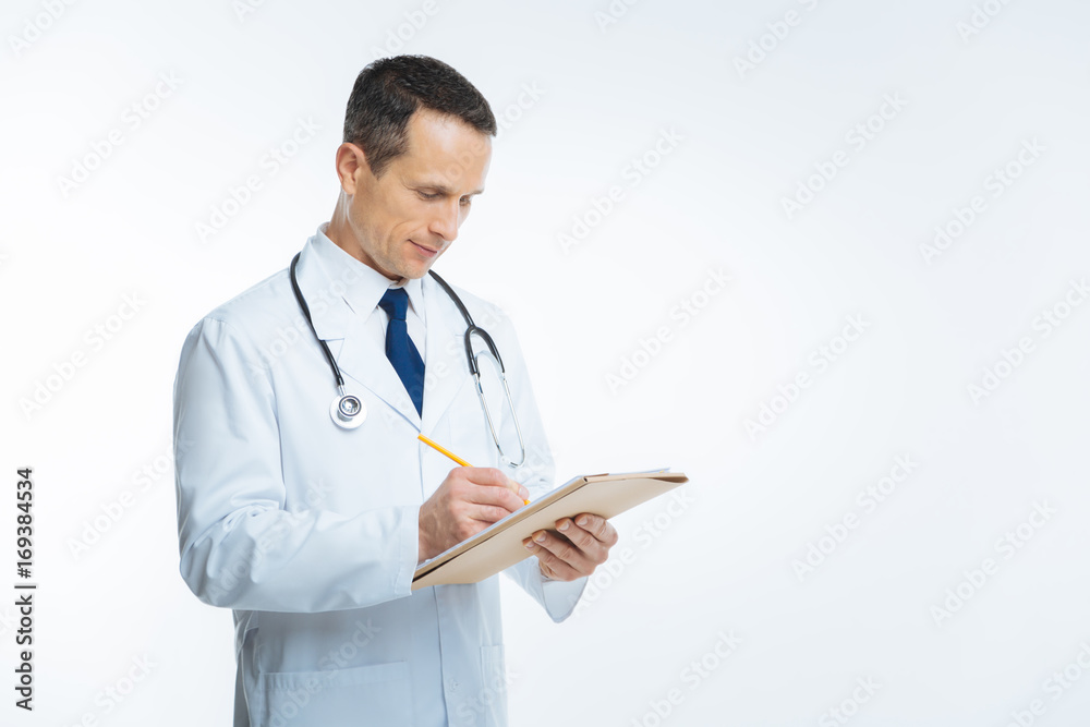 Male doctor in white coat making notes over background Male doctor in white coat making notes over background