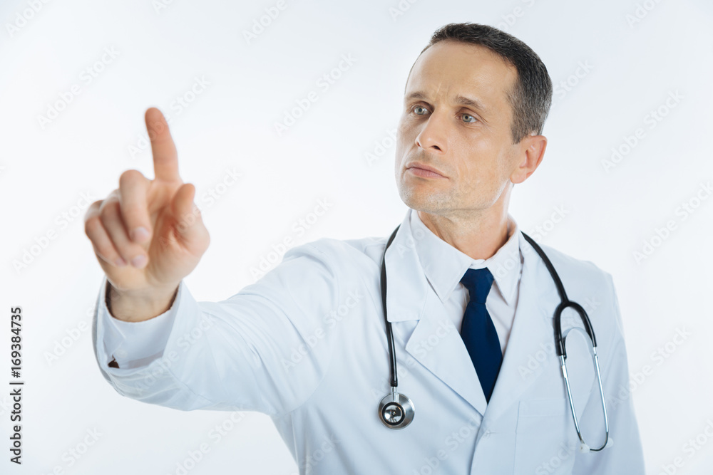 Serious mature doctor using invisible touchscreen alone Serious mature doctor using invisible touchscreen alone