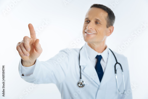 Cheerful medical professional pretending to touch invisible screen