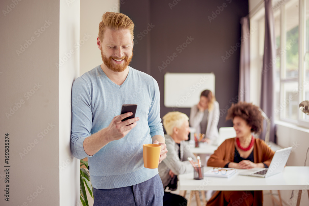 Businessman using smart phone in modern office. In background multi ethnic team Businessman using smart phone in modern office. In background multi ethnic team