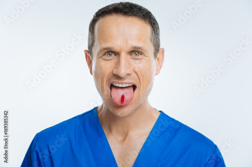 Excited medical worker showing tongue with pill