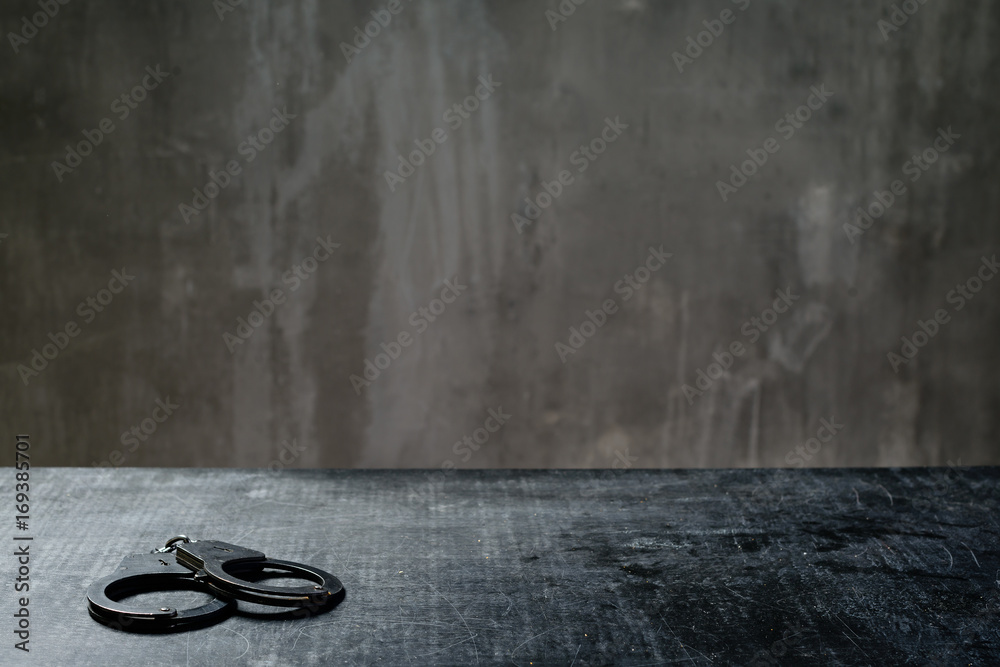 front view of metal handcuffs on table in the interrogation room - obrazy, fototapety, plakaty 