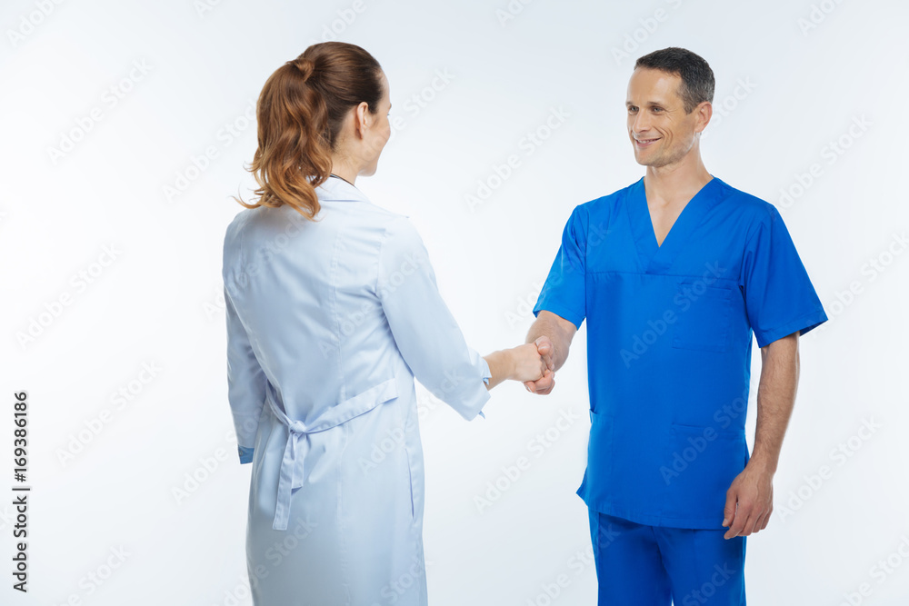 Joyful male doctor greeting his female colleague Joyful male doctor greeting his female colleague