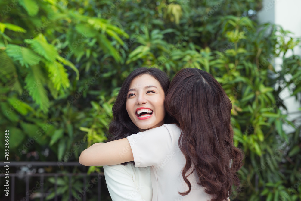 Happy young women friends well-dressed smiling while hugging together Happy young women friends well-dressed smiling while hugging together