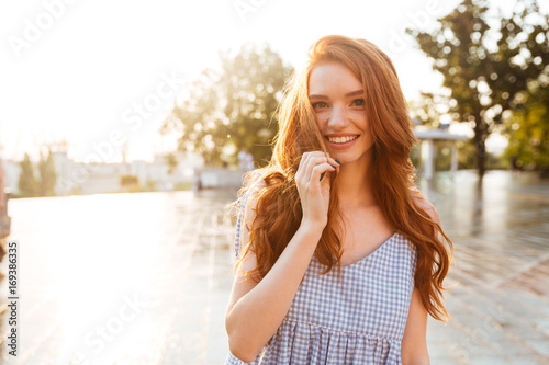Happy pretty redhead girl with long hair looking at camera