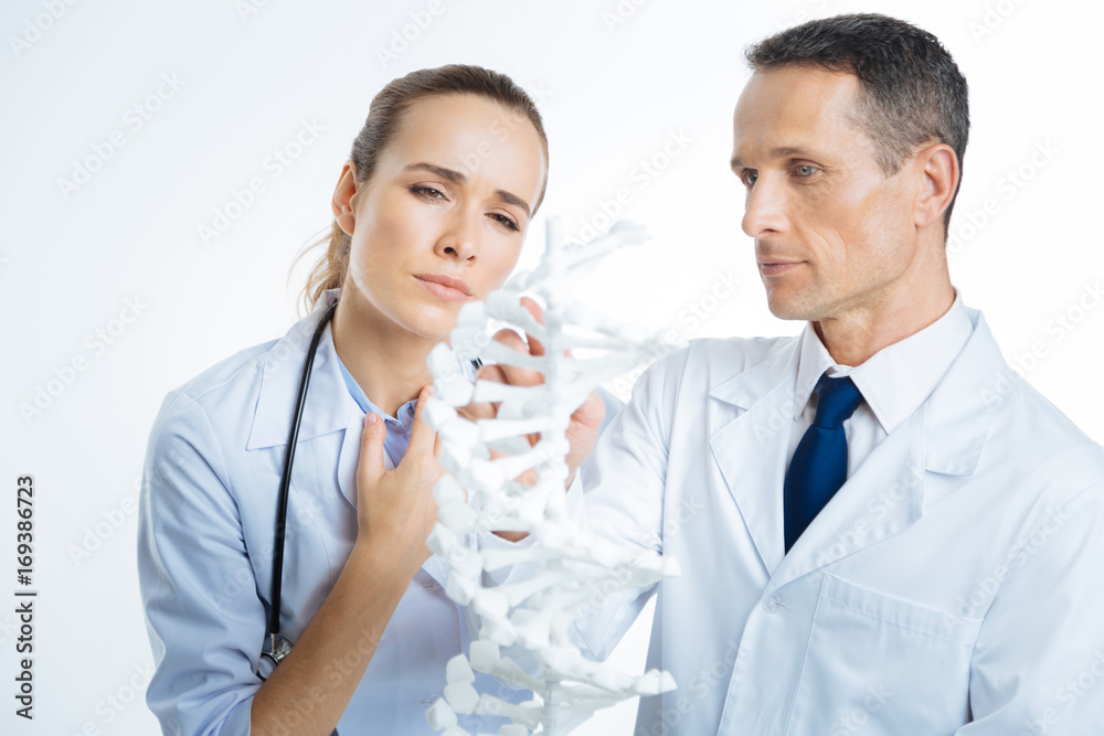Close up of pensive physicians looking at dna model Close up of pensive physicians looking at dna model