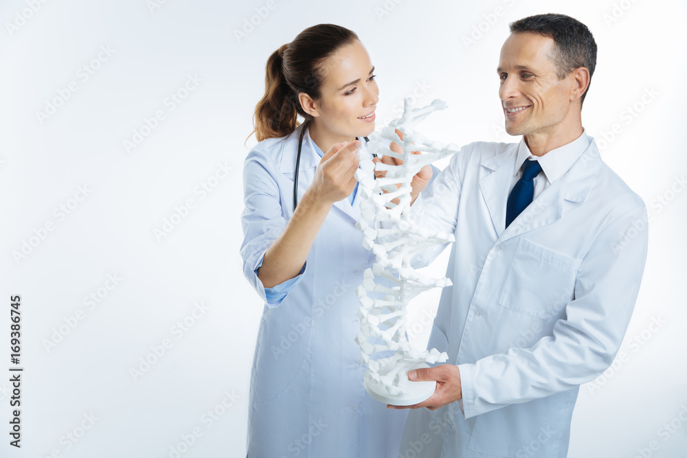 Friendly coworkers talking over three dimensional dna model Friendly coworkers talking over three dimensional dna model