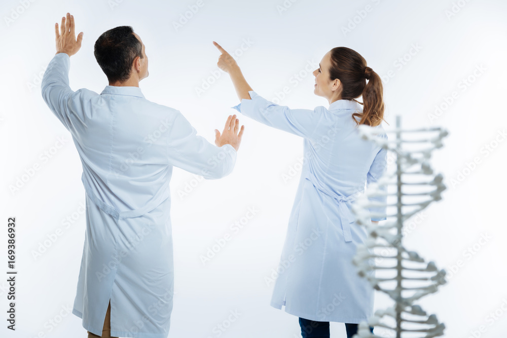 Joyful medical coworkers using invisible screen while studying genetics