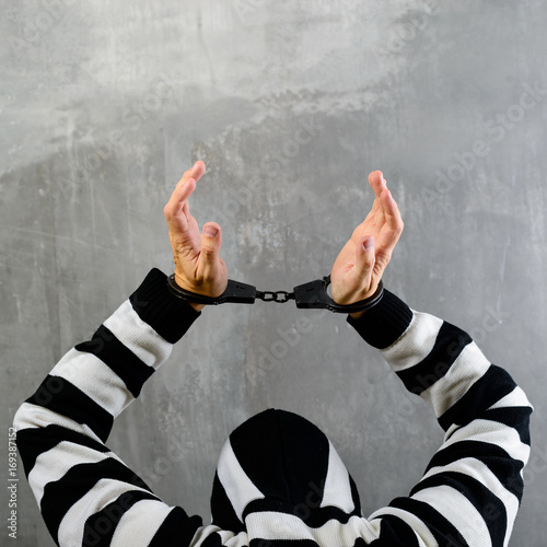 rear view of unidentified prisoner in prison stripped uniform standing in the dark interrogation room. Concept of detention and imprisonment photo