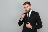 Confident handsome businessman in suit pointing finger at camera