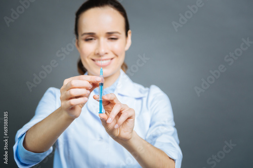Positive minded physician checking syringe before injection