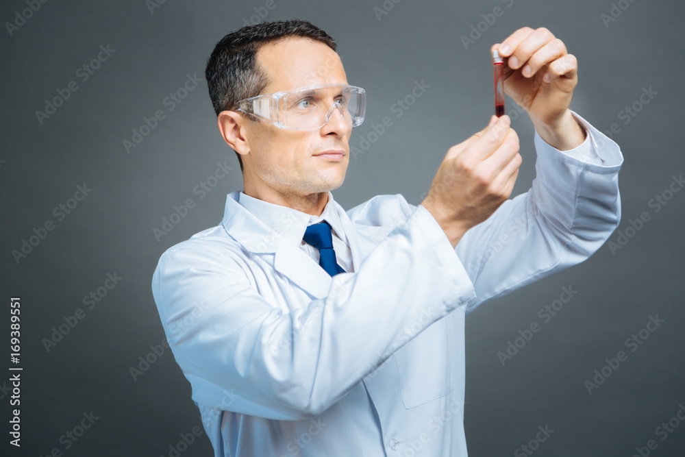 Confident medical professional examining blood sample Confident medical professional examining blood sample