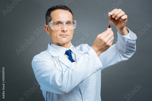 Mature doctor holding test tube with blood sample