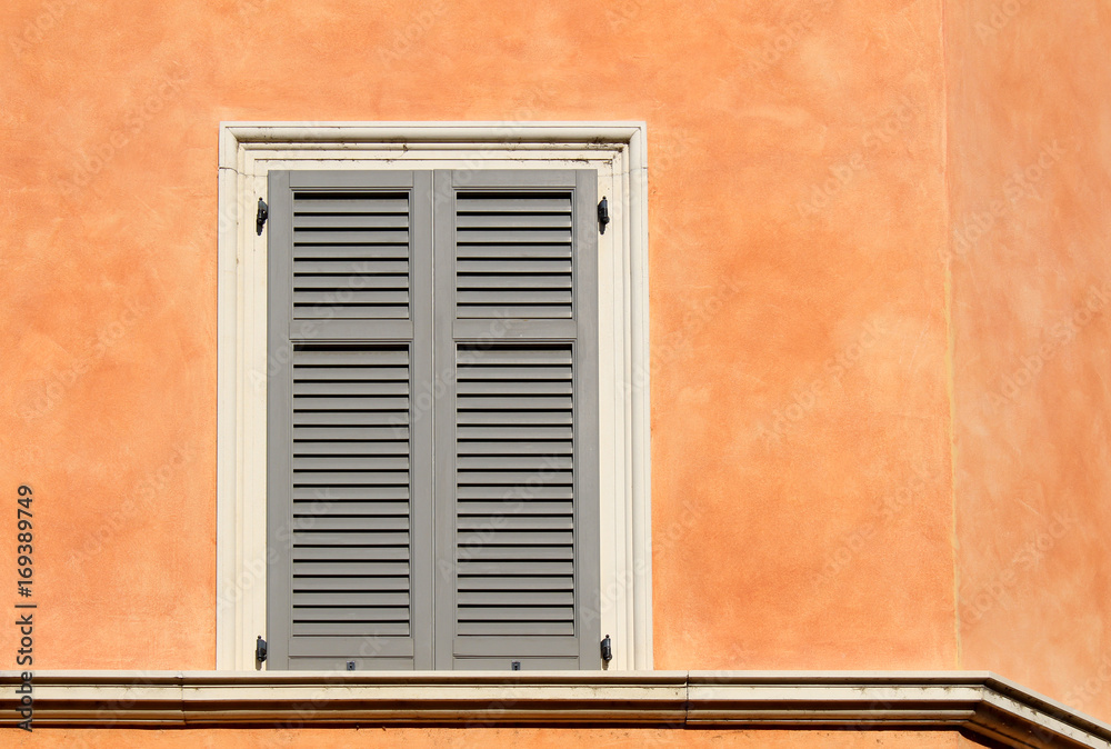 Closed shutter window on an orange wall