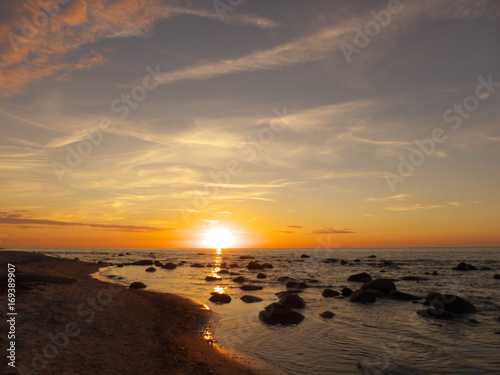 Sonnenuntergang am Meer mit Steinen im Wasser, gleißend