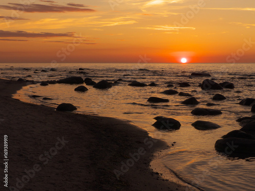 Sonnenuntergang am Meer mit Steinen im Wasser, Totale