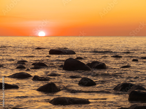 Sonnenuntergang am Meer mit Steinen im Wasser