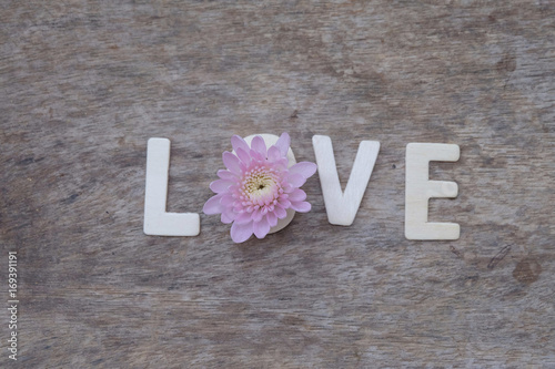 Love words made of wood and flowers on wooden background. 