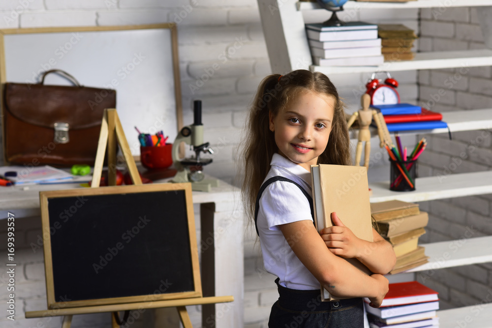 Back to school concept. Schoolgirl holds book on classroom background Back to school concept. Schoolgirl holds book on classroom background