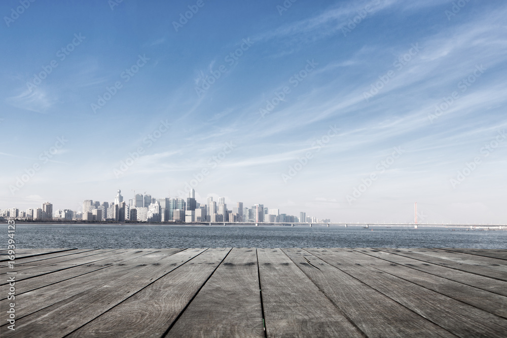 empty wooden floor with cityscape of modern city near water
