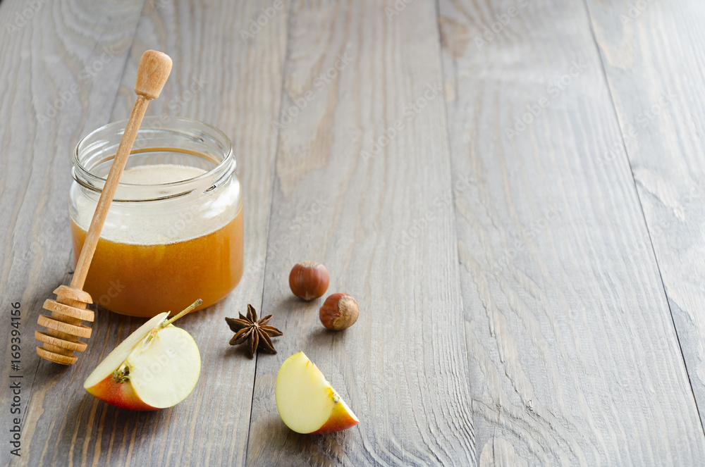 Jar of honey with honey stick, slices of apple, hazelnuts and anise Jar of honey with honey stick, slices of apple, hazelnuts and anise