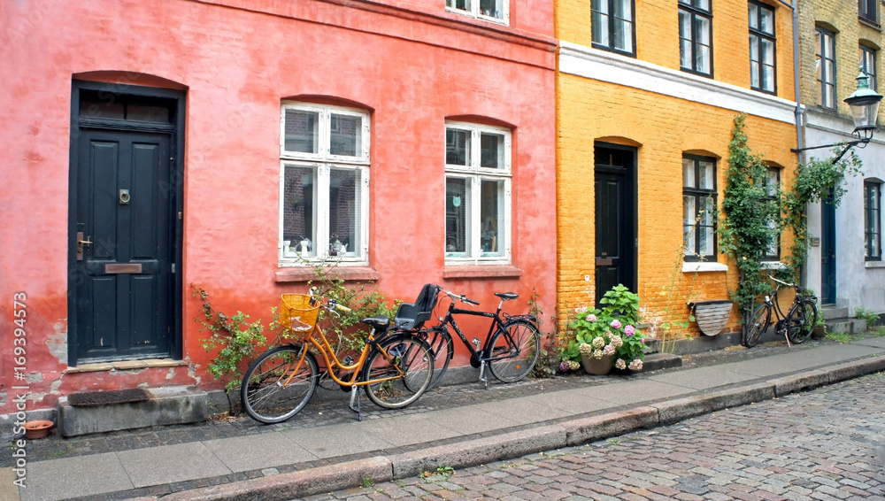 Colorful street, doors, windows, red and yellow walls and bikes with basket in old town, Copenhagen, Denmark