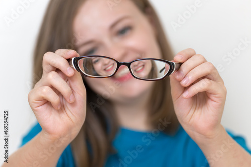 Girl is checking her glasses, soft background and glasses in focus