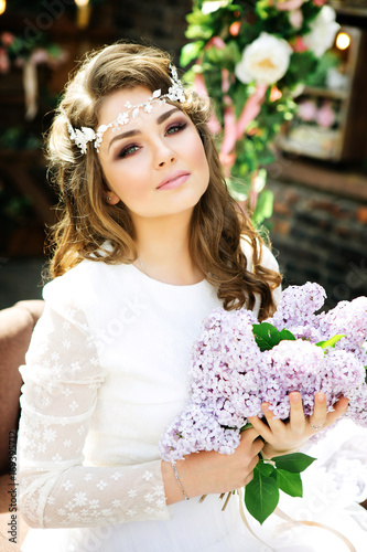 Stylish bride with a bright make-up and a gentle hairstyle. Summer girl with bouquet of flowers in hands